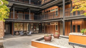 Een meerlaags gebouw met een binnentuin, voorzien van zitplaatsen buiten en plantenbakken.