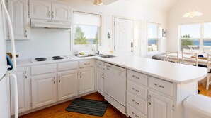 A modern kitchen with white cabinetry, a built-in stove, and a large island with a sink.