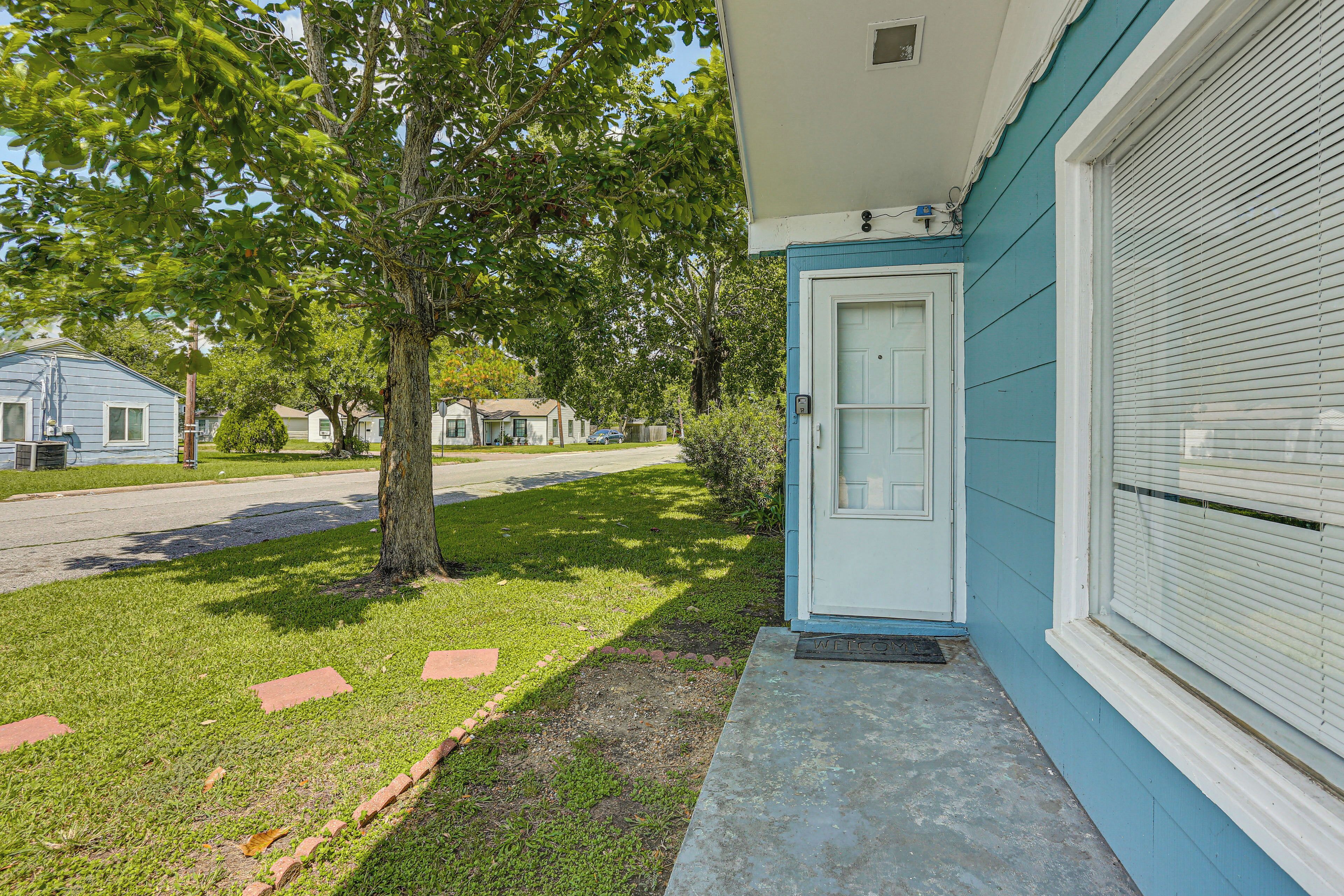 A single-story house with a front door, a small porch, and a tree in the yard.