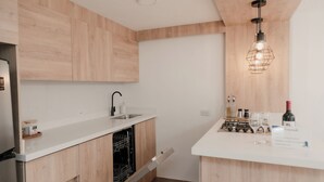 A modern kitchen with wooden cabinets, a white countertop, a dishwasher, a sink, and a wine bottle.