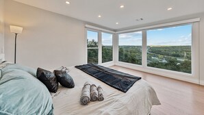 A bedroom with a large window, a bed with pillows and a rug, and a floor lamp. - Casa Mattia 4BR Luxury Mountain Home (Suffern)