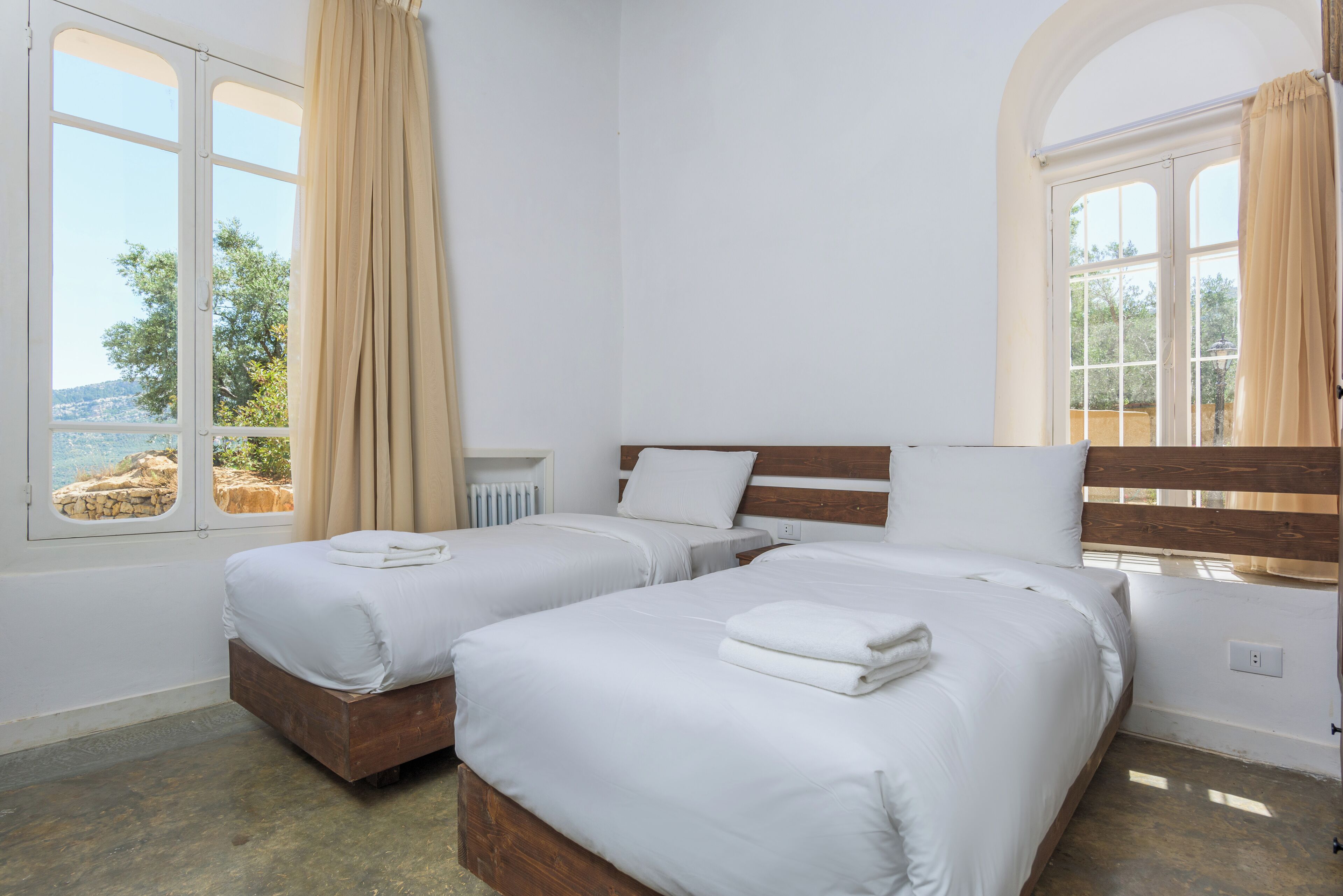 A room with two beds, a wooden headboard, and a view of the sea.