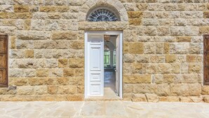 Un bâtiment en pierre doté d’une grande fenêtre en arc de cercle et d’une porte blanche.