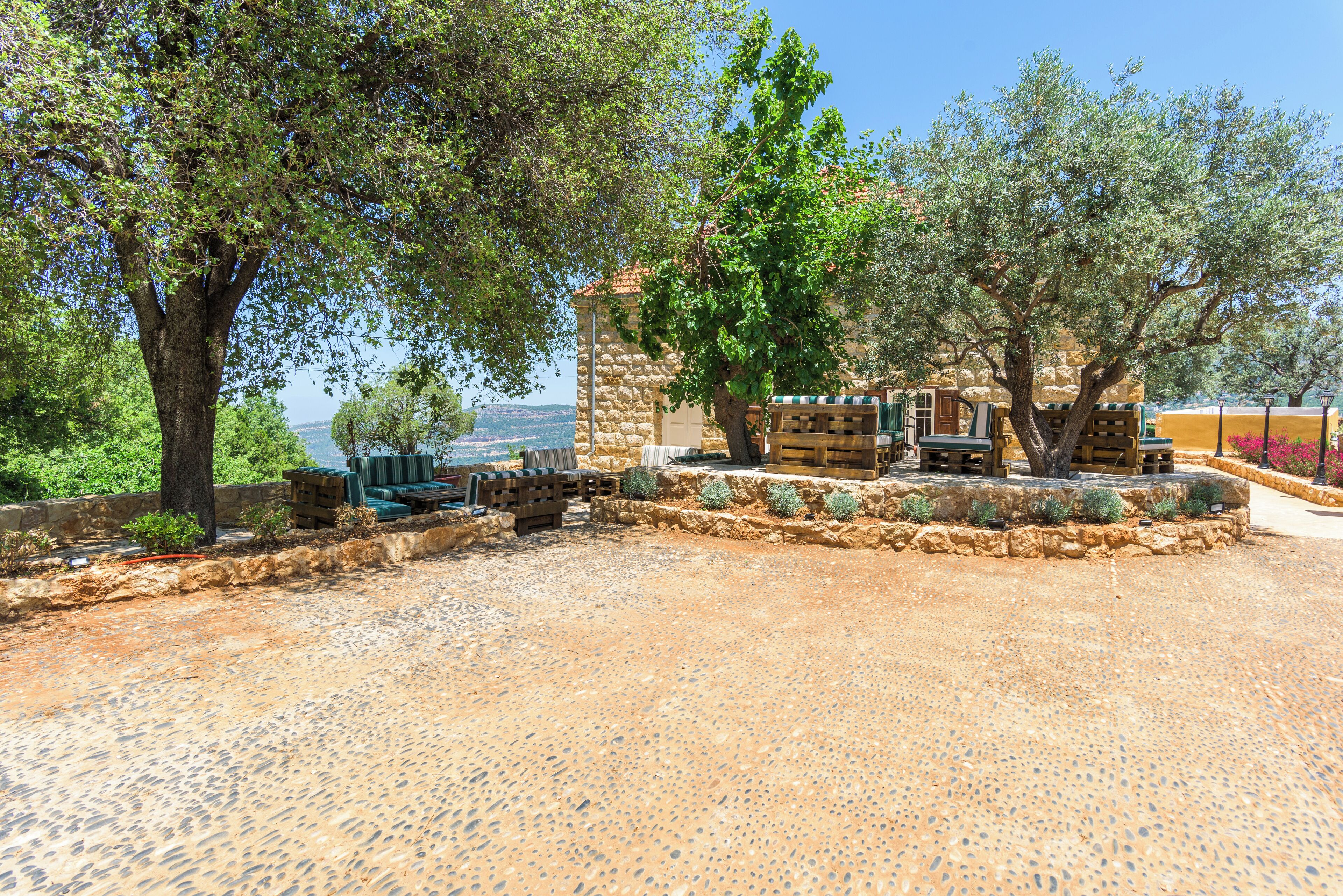 A courtyard with stone flooring, outdoor seating, and trees.