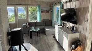 Ein gemütliches Zimmer mit einer Couch, einem kleinen Tisch, einem Fernseher und einem Schrank.