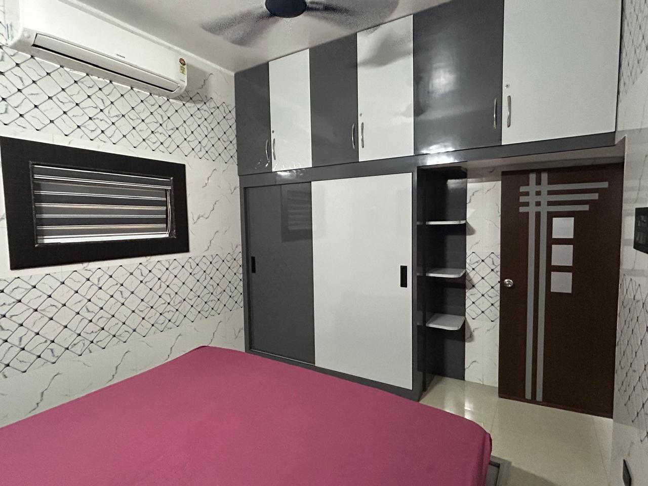 Ein Schlafzimmer mit Bett, Kleiderschrank und einem Fenster mit Jalousien.