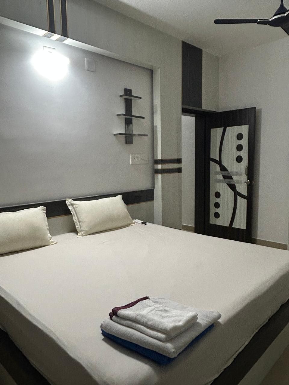 Ein Hotelzimmer mit einem großen Bett, einem Nachttisch, einem Spiegel und einer Tür mit dekorativem Design.