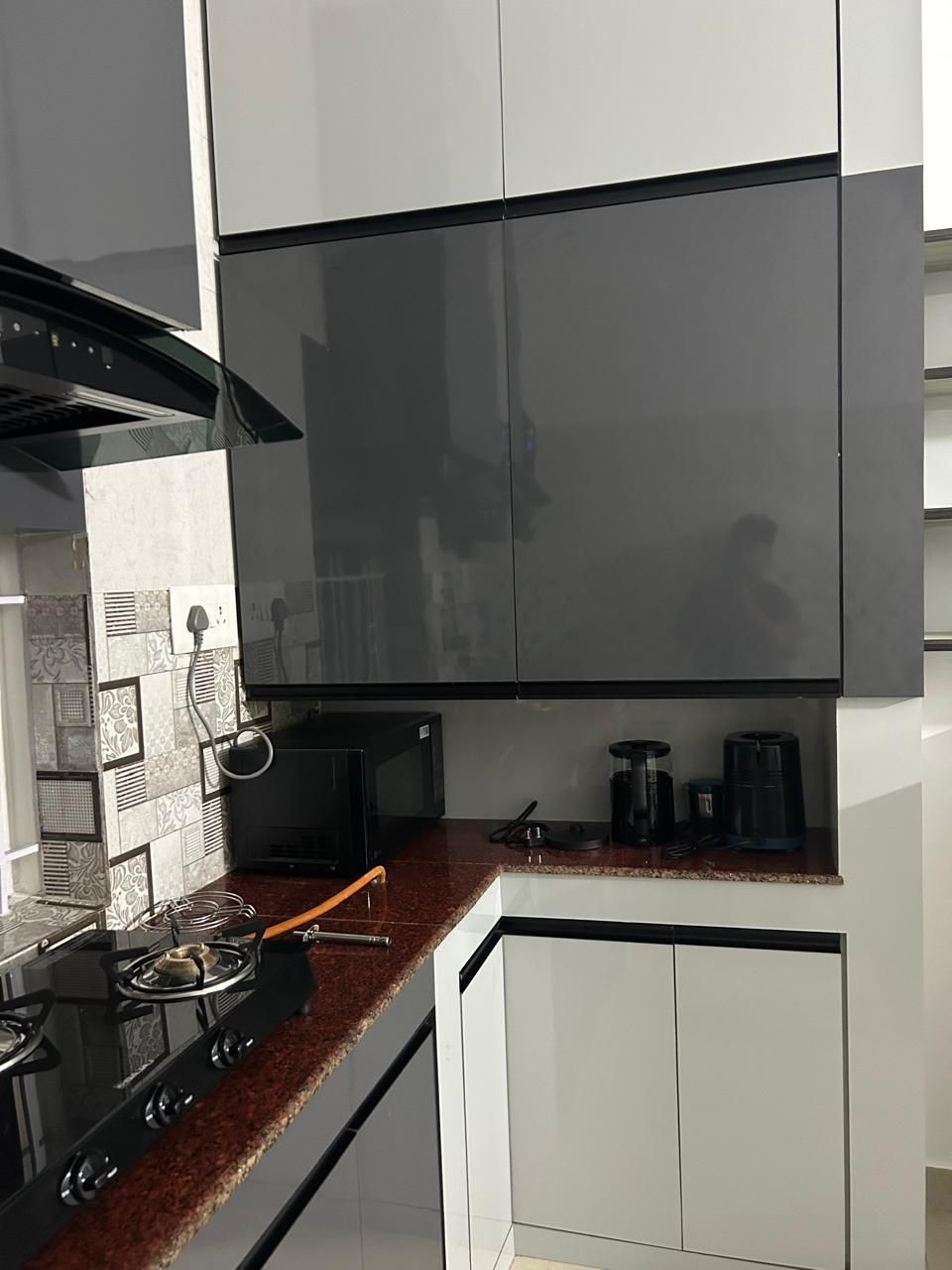 Uma cozinha moderna com armários brancos, fogão preto e micro-ondas.
