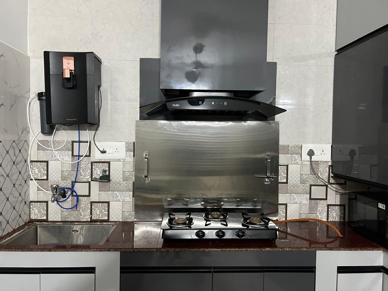 Une cuisine équipée d’une hotte en acier inoxydable, d’une cuisinière à gaz et d’un distributeur d’eau.