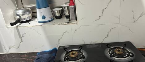 Uma cozinha com fogão a gás, chaleira e máquina de café.
