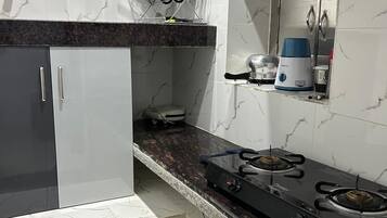 A kitchen with a gas stove, a microwave, and a coffee maker on the countertop.