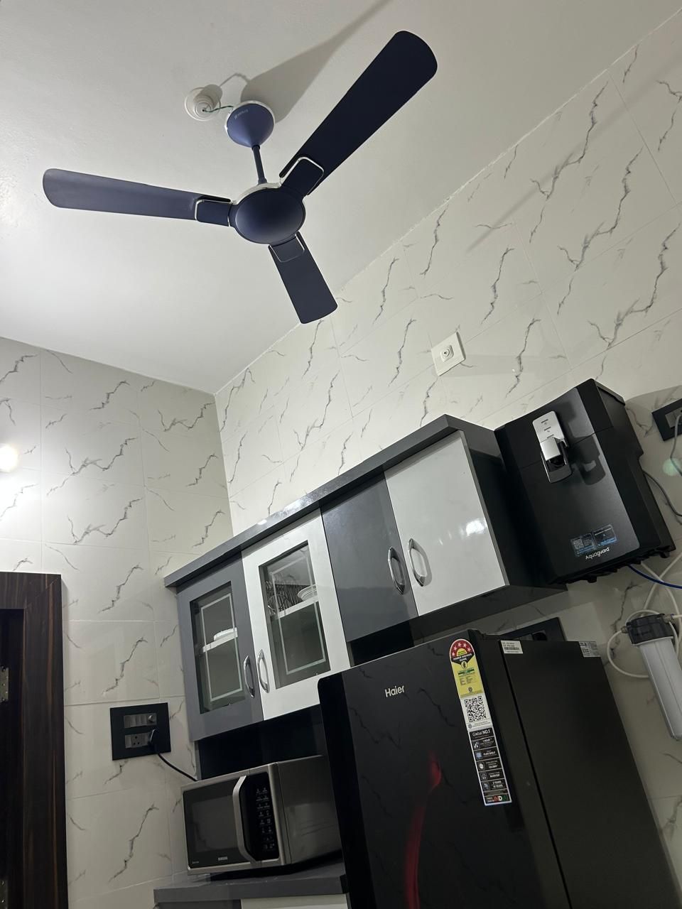 Eine Küche mit Deckenventilator, Mikrowelle und Kühlschrank.