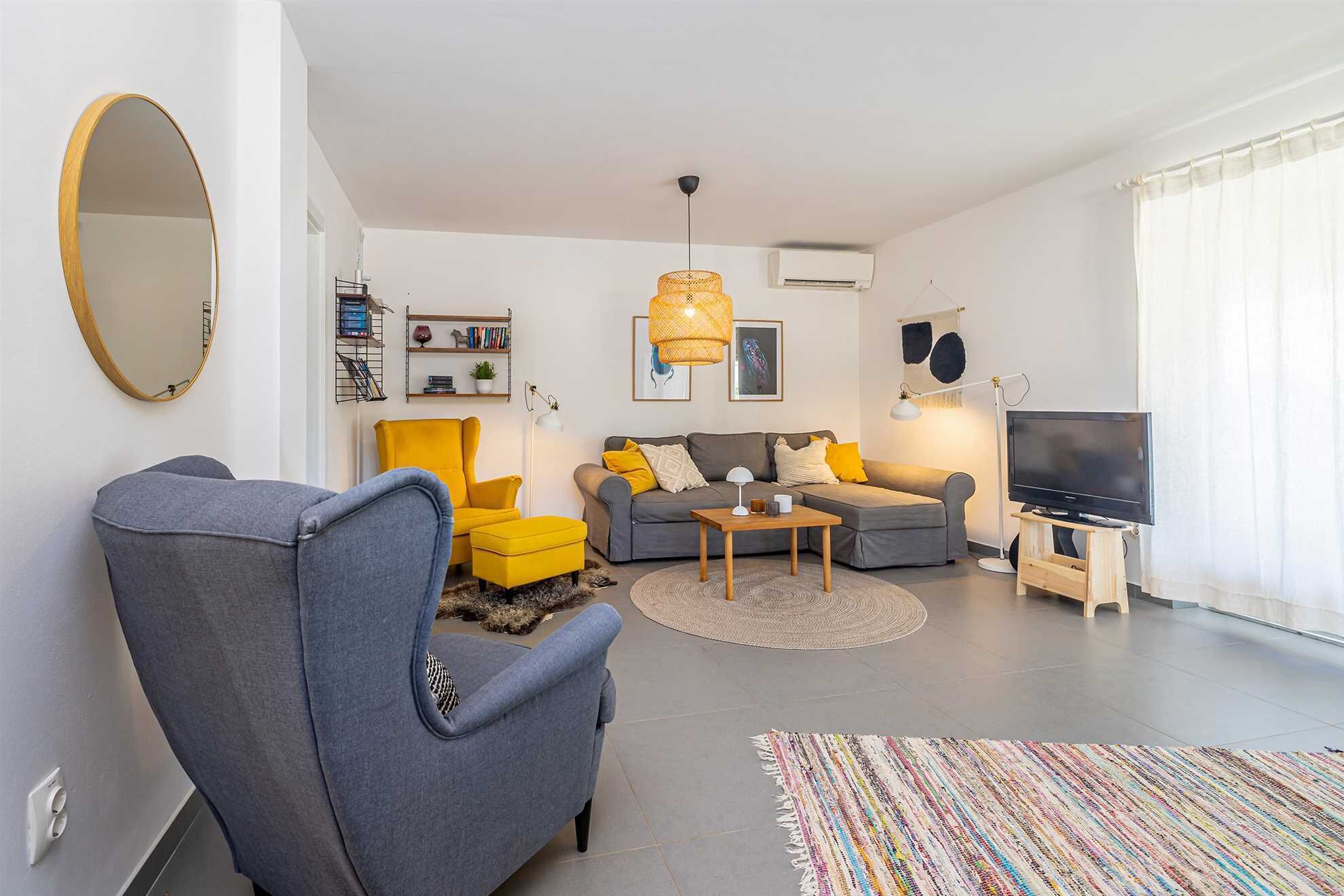 A modern living room with a sofa, armchair, and a television.