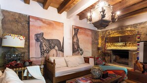 A cozy living room with a sofa, a fireplace, and artwork on the walls.