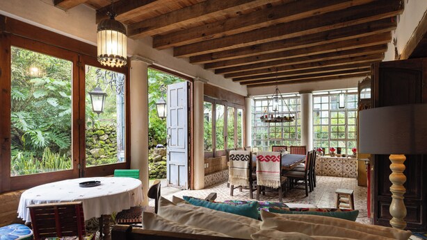 A spacious room with a large window, a dining area, and a cozy seating area.
