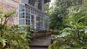 A rustic building with a large window overlooking a garden.