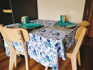 Een eettafel met een tafelkleed met bloemenprint, twee stoelen en een paar teal- en gouden borden.