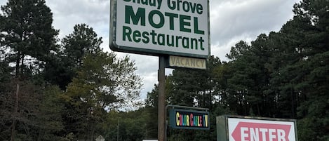 En skylt för ett motell med texten ”Lediga rum”, en vägvisningsskylt för ”Shady Grove Motel Restaurant” och en skylt med texten ”In” vid en väg.