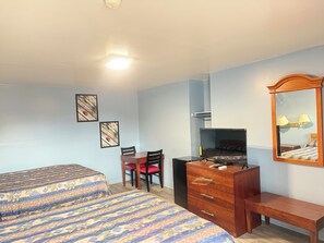 A bedroom with two beds, a wooden dresser, a desk with a chair, and a mirror. - Shady Grove Motel (Ashland)