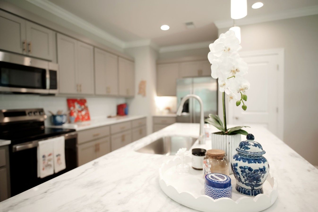 A modern kitchen with marble countertops, stainless steel appliances, and a decorative orchid centerpiece.