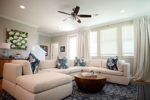 A living room with a sectional sofa, a coffee table, and a ceiling fan. - The Lily Loop Retreat (Oxford)