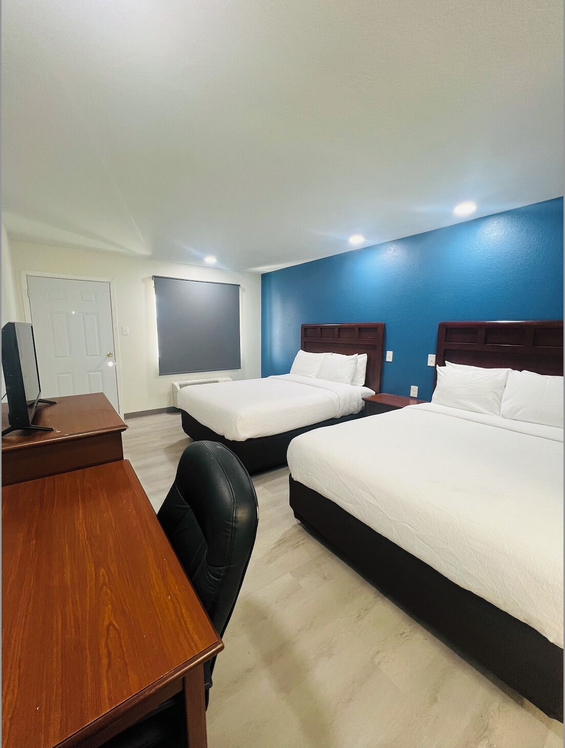 A hotel room with two beds, a desk, and a chair.