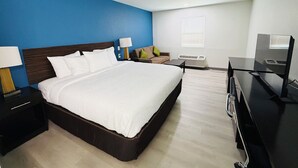 A modern hotel room with a large bed, a desk, a TV, and a sofa.