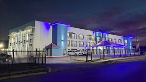 A multi-story hotel with a modern design, featuring balconies and a gated entrance. - Hallmark Inn and Suites (San Antonio)