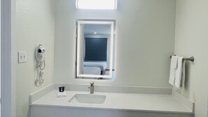 A bathroom with a white sink, a mirror, a telephone, and a towel rack.