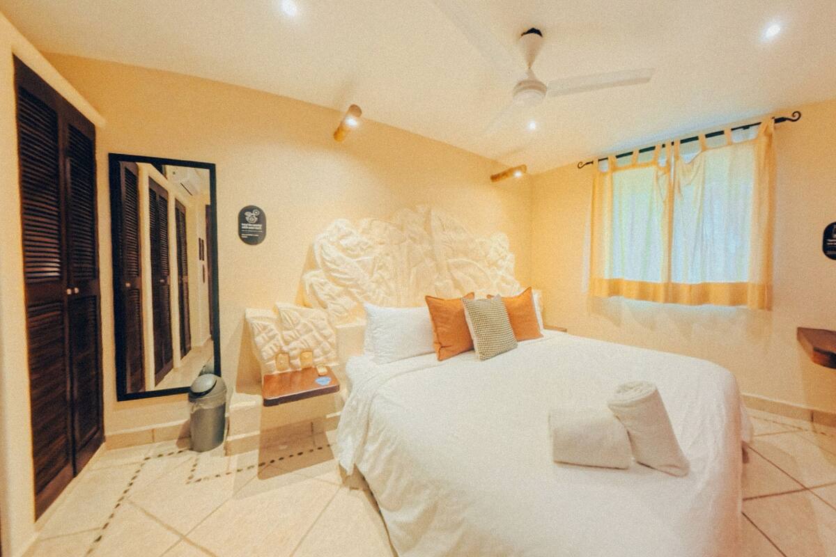 Een hotelkamer met een groot bed, een plafondventilator en een raam met gordijnen.