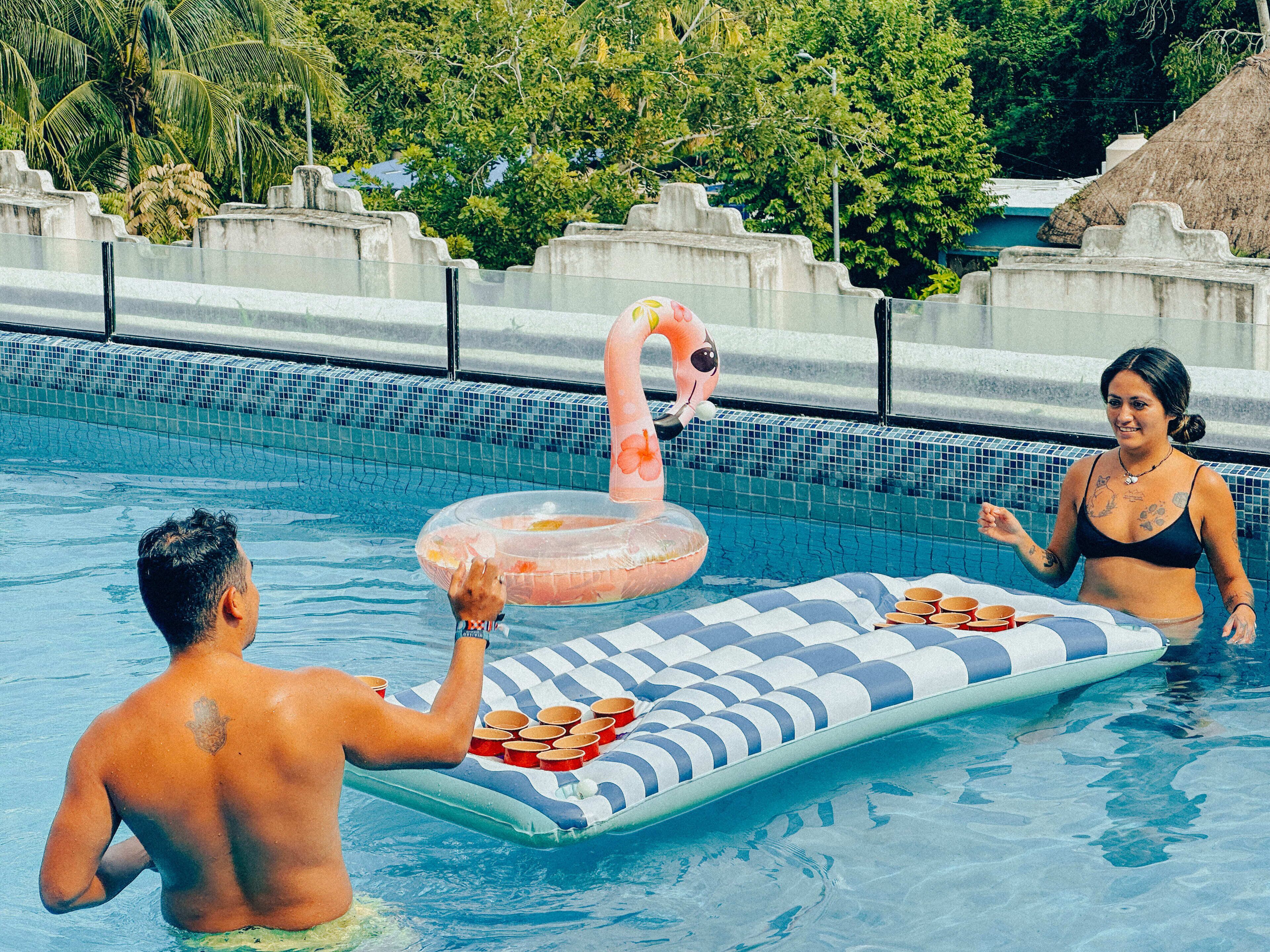 Ein Swimmingpool mit einem Flamingo-Schwimmpferd und einer Liege mit Schachbrettmuster.