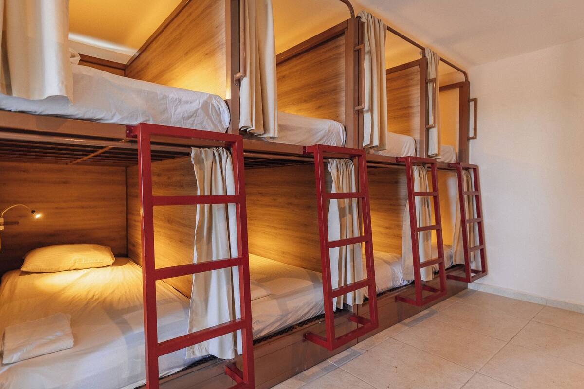 Een kamer met stapelbedden, houten wanden en gordijnen.