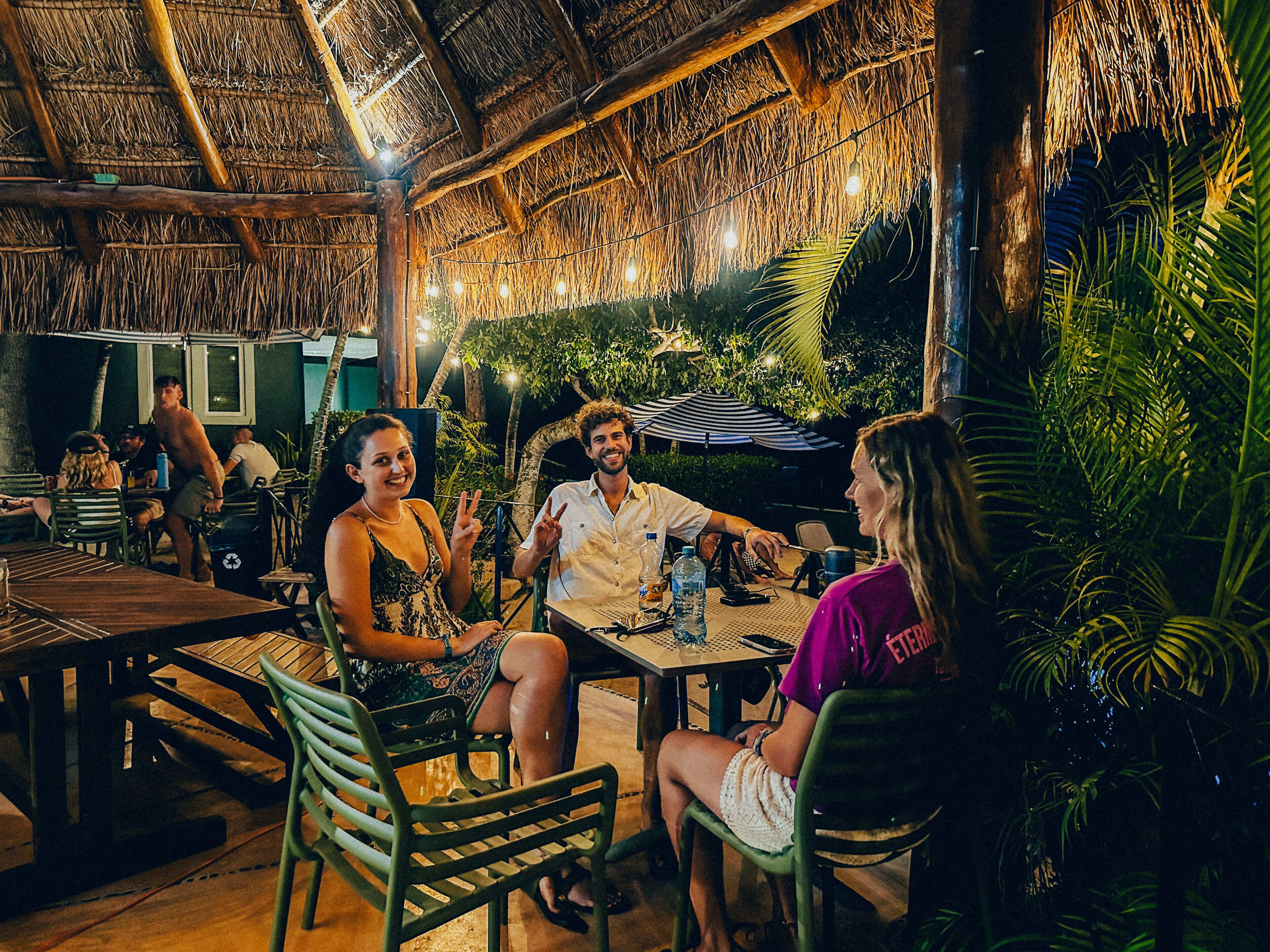An outdoor dining area with thatched roofs, wooden tables, and chairs.