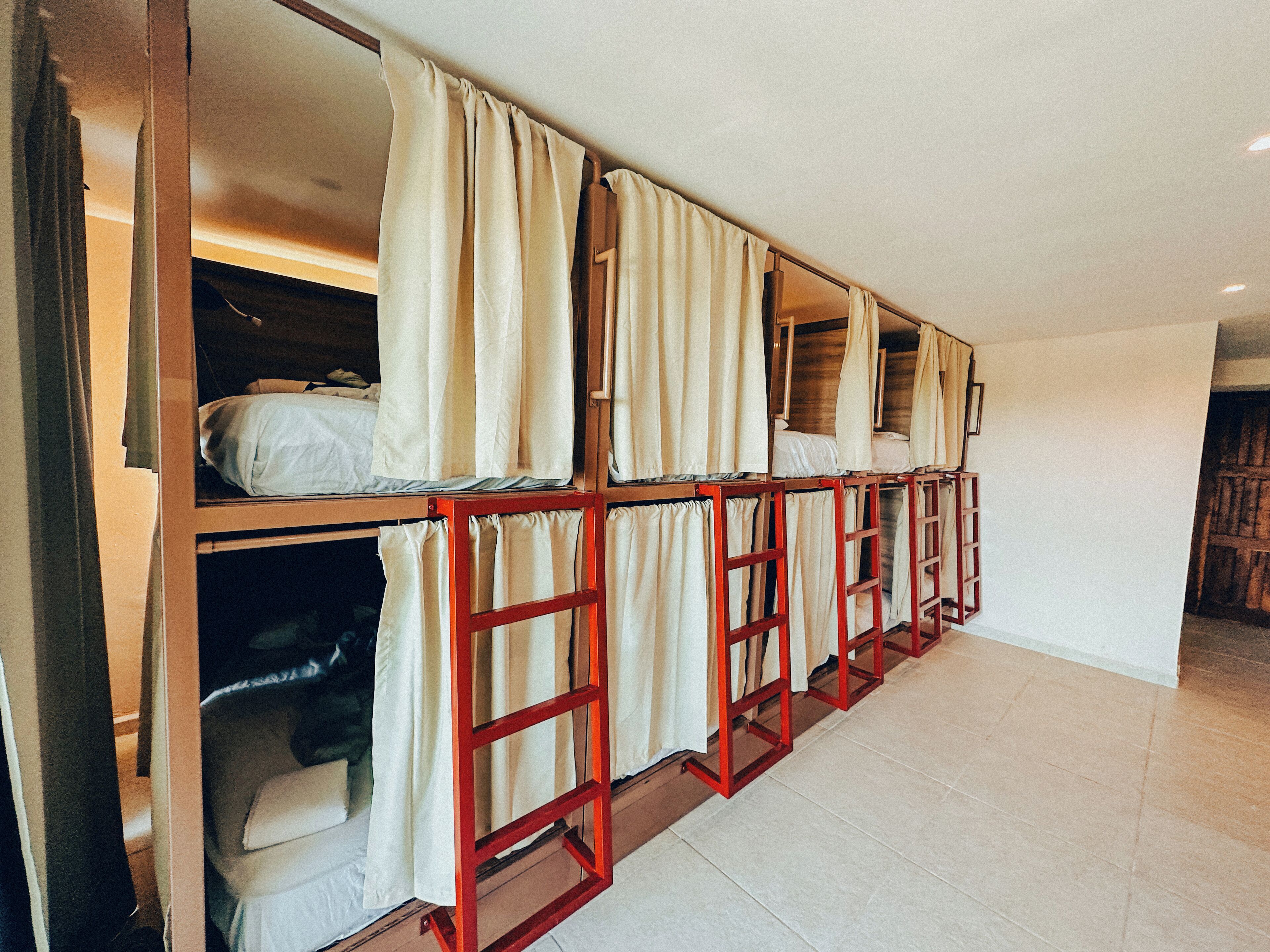A dormitory-style room with bunk beds, each with a curtain.