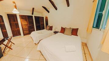 A hotel room with two beds, wooden shutters, a tiled floor, and a window.