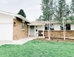 A two-story house with a brick exterior, a front porch, and a small front yard. - Wonderful 5-bedroom house with AC in Centennial (Centennial)