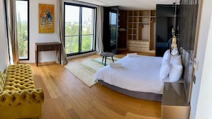 Camera da letto moderna con un letto grande, pavimento in legno, un armadio e vista sulla città attraverso un'ampia finestra.