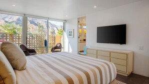 Een slaapkamer met een groot bed, een televisie en uitzicht op bergen vanaf het balkon.
