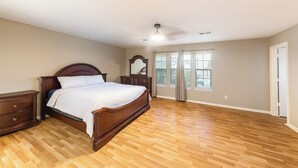 A bedroom with a wooden bed, a nightstand, a dresser, and a large window with blinds. - Pet-friendly 3BR Near First Colony Mall (Houston)