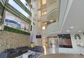 Um hall de hotel com parede de pedra, área de estar e escadaria que leva aos andares superiores.