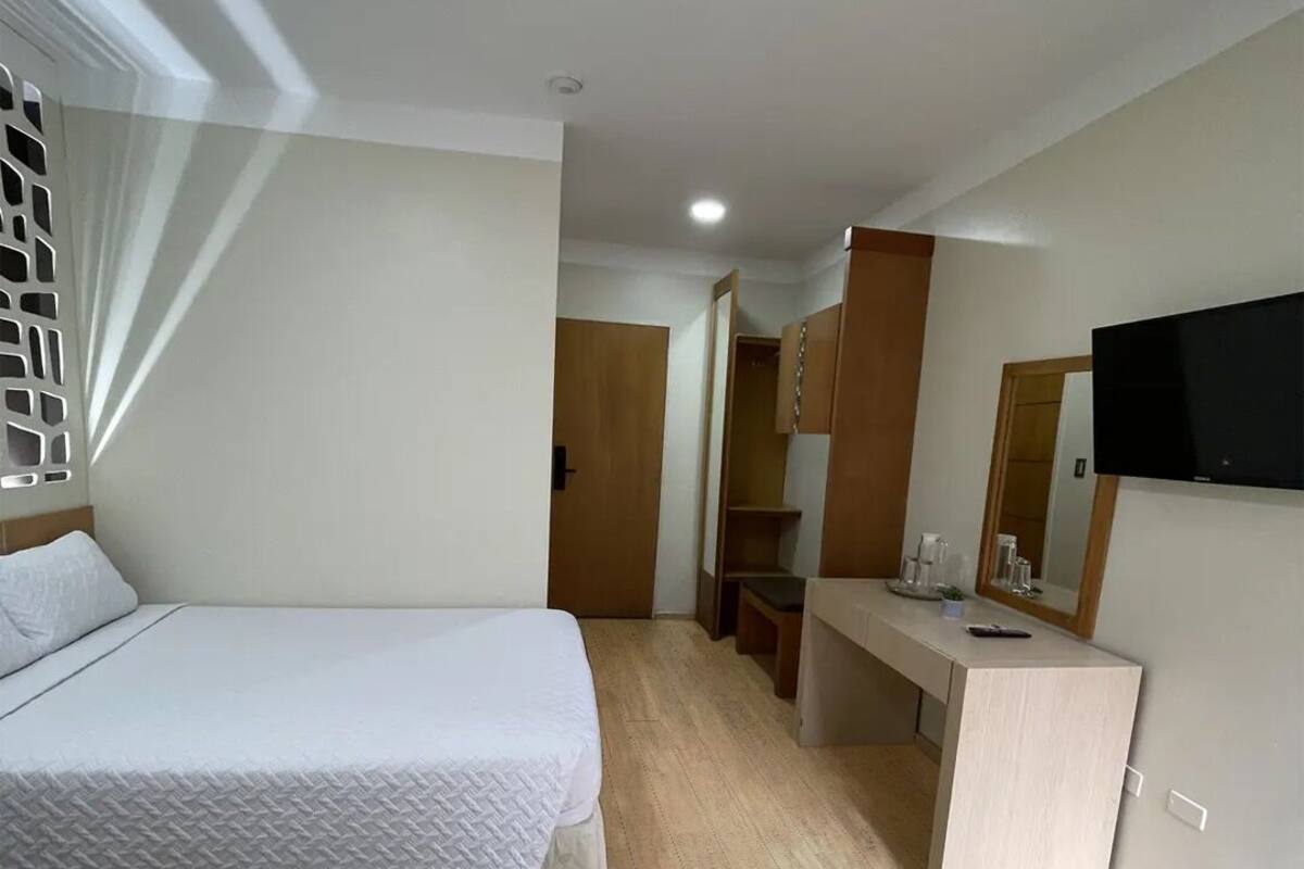 Ein Hotelzimmer mit zwei Betten, einem Schreibtisch, einem Spiegel und einem Fernseher.