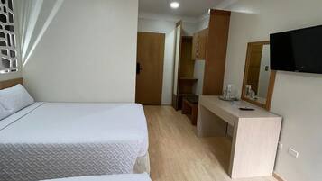 A hotel room with two beds, a desk, a mirror, and a television.