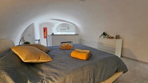 Une chambre avec un grand lit, une table de chevet, une armoire et une vue sur la cuisine.