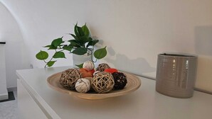 A white table with a wooden plate holding decorative balls and a potted plant. - In the beating heart of the city-historical center (Napoli)