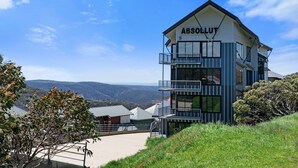 Un edificio de varios pisos con el letrero 'ABSOLUT' en la parte superior, rodeado de vegetación y vistas a montañas distantes.