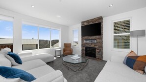Una sala de estar moderna con chimenea de piedra, ventanas amplias y un espacio de descanso acogedor.