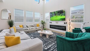 Ein modernes Wohnzimmer mit einem Ecksofa, einem grünen Sessel, einem Couchtisch und einem Flachbildfernseher.