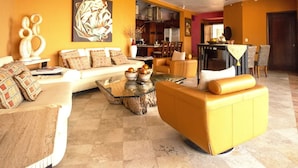 A living room with a sofa, armchairs, a coffee table, and a painting on the wall. -  Penthouse suite with dipping pool, palapa & private sunroof overlooking the Bay (Puerto Vallarta)