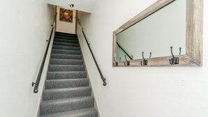 Una escalera con barandilla, un espejo adosado a la pared y un cartel de seguridad contra incendios.