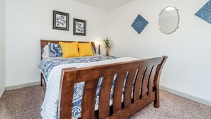 Un dormitorio con una cama de madera, una mesita de noche con lámpara y decoración mural.